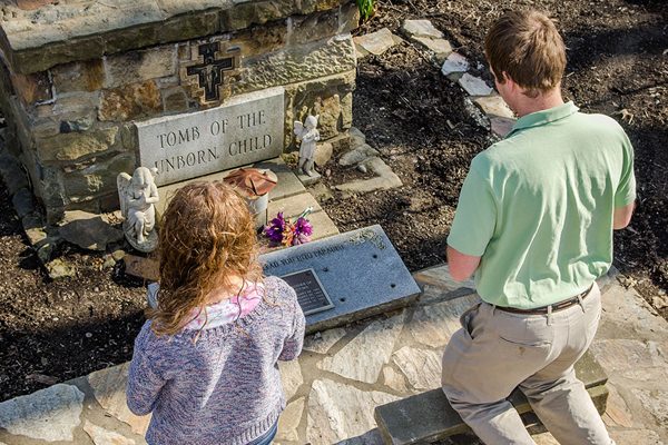 two students kneeling before the tomb of the unborn child